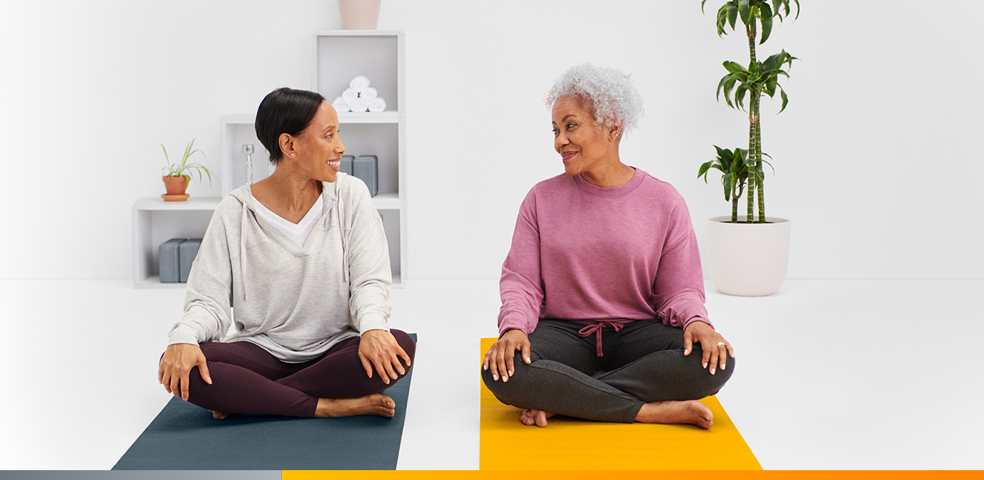 Dos mujeres sentadas sobre tapetes de yoga mirándose mutuamente