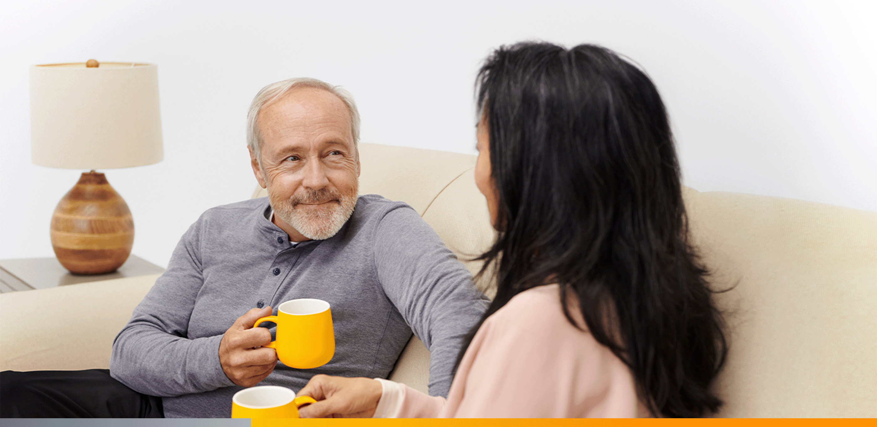 Pareja sentada en el sofa aguantado las tazas